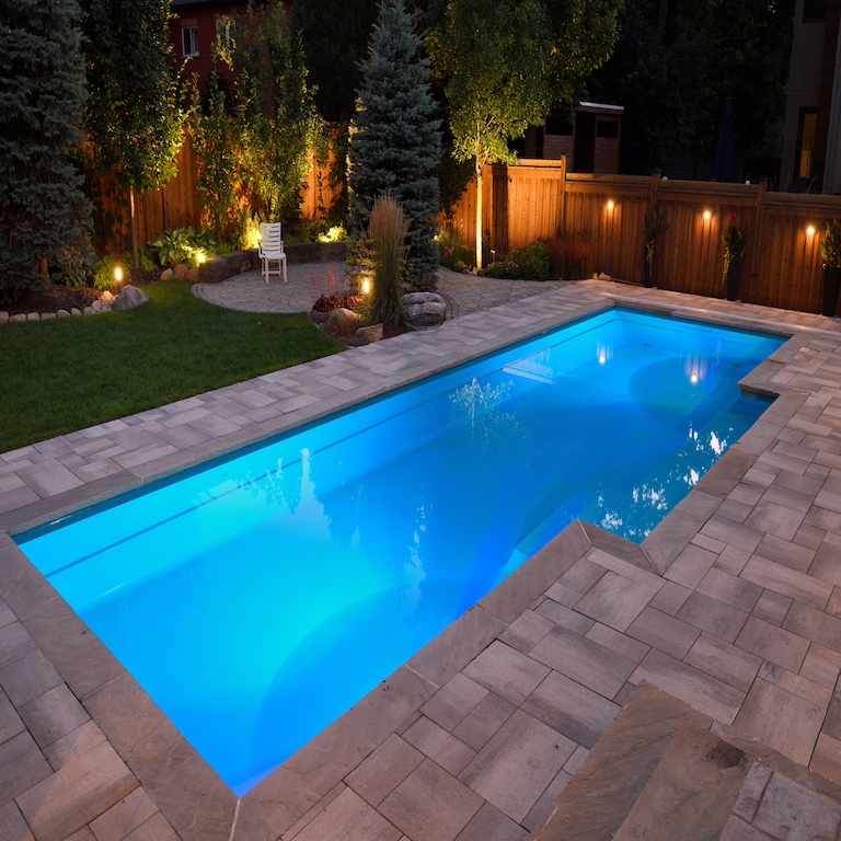 Lights in swimming pool in the backyard and a deck at night