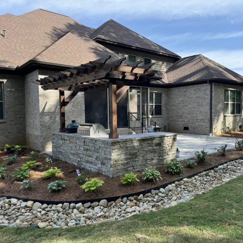 Backyard landscape with rocks and plants in Owens Cross Roads, AL